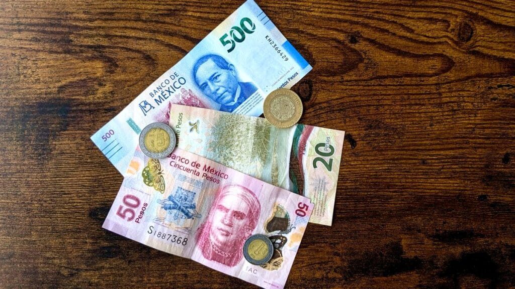Mexican pesos and credit cards on a wooden table, representing banking in Mexico for expats